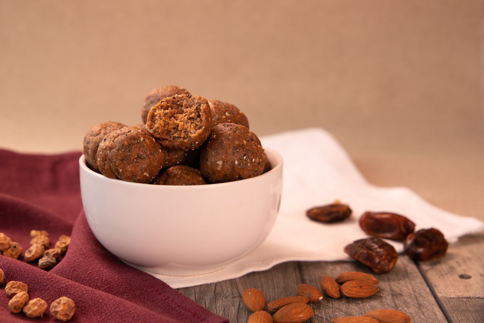 Bolinhas de tâmara e frutos secos numa taça, com tâmaras e amêndoas ao lado