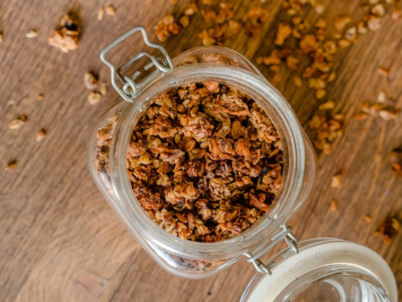 Granola caseira num frasco de vidro sobre uma mesa de madeira