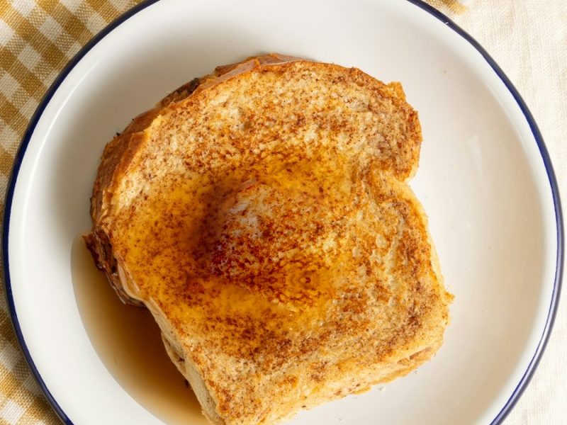Rabanada dourada com canela e calda num prato branco