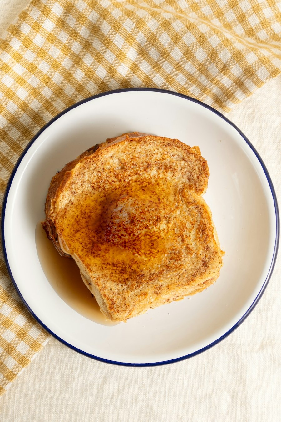 Rabanada dourada com canela e calda num prato branco