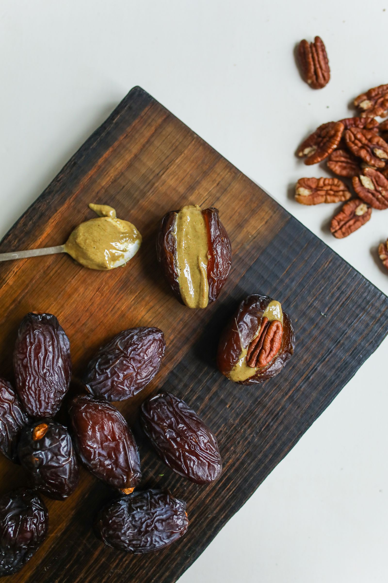 Tâmaras Medjool recheadas com noz-pecã e manteiga de frutos secos numa tábua de madeira